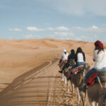 Frauen reiten auf Kamelen durch die Sanddünen der Wüste