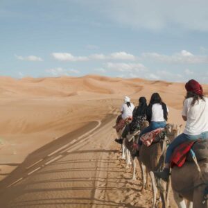 Frauen reiten auf Kamelen durch die Sanddünen der Wüste