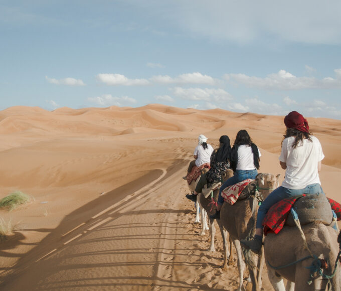Frauen reiten auf Kamelen durch die Sanddünen der Wüste