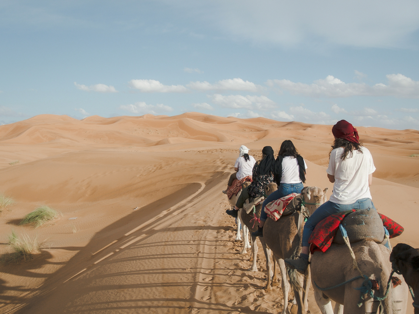 Frauen reiten auf Kamelen durch die Sanddünen der Wüste