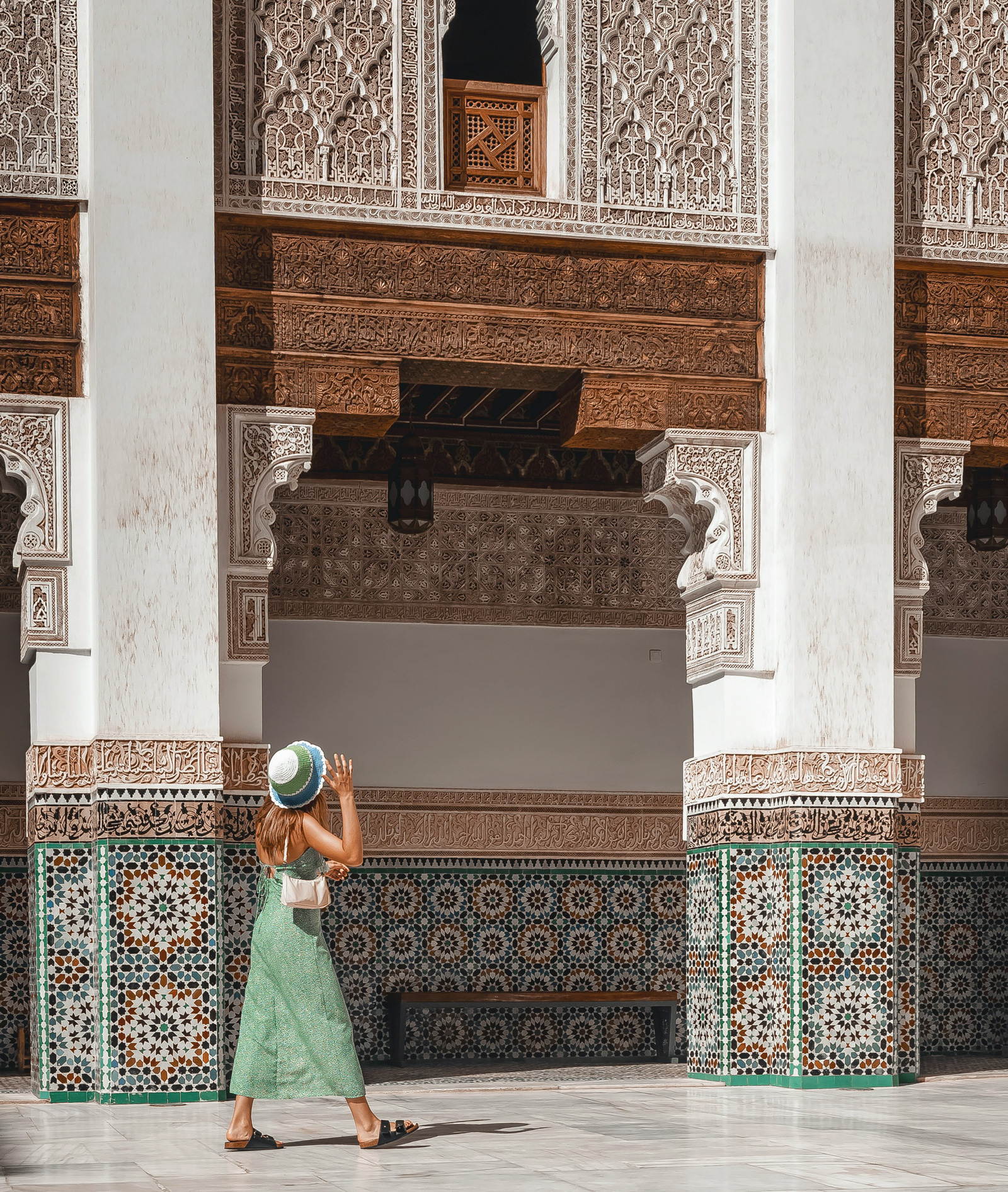 Frau in einem Innenhof mit marokkanischen Mosaiken in Marrakesch