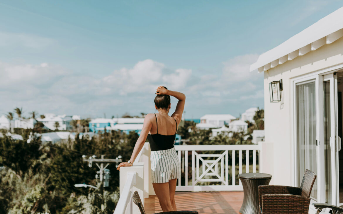 Alleinreisen als introvertierte Frau: Reisende genießt eine ruhige Auszeit auf dem Balkon ihrer Unterkunft